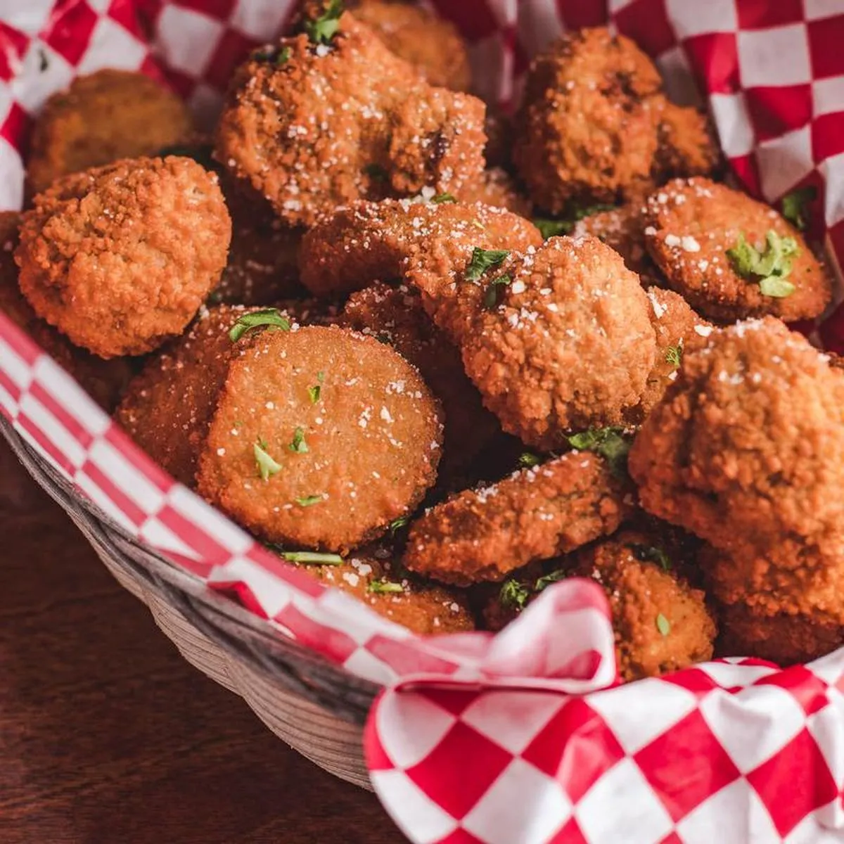 Basket of breaded fried mushrooms and zucchini dusted with parmesan