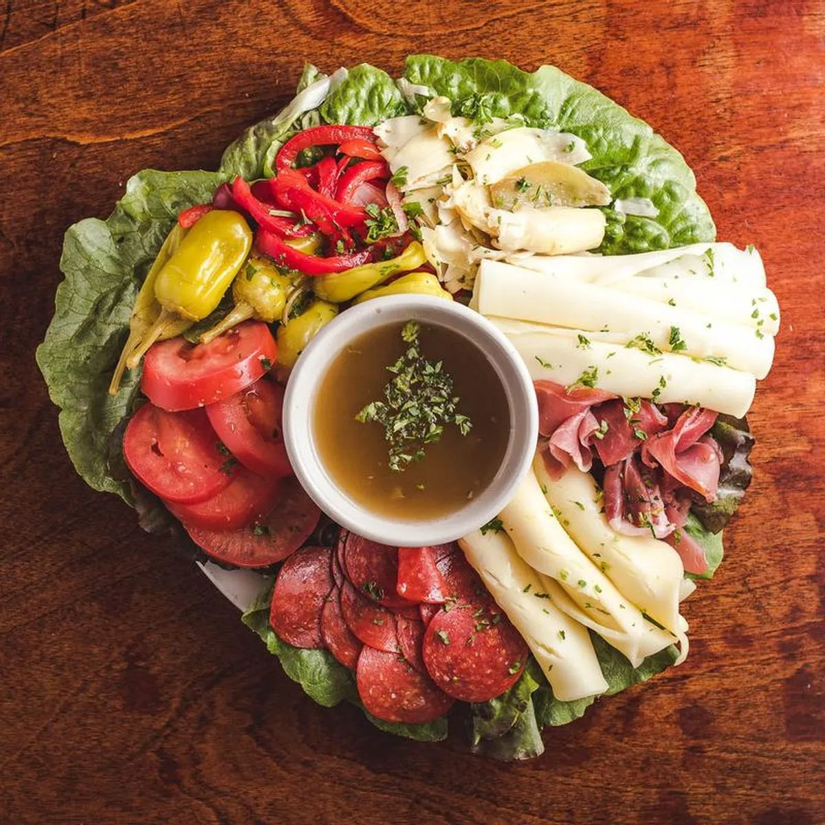 Overhead antipasto platter of salami, provolone, prosciutto, artichokes, peppers and tomato