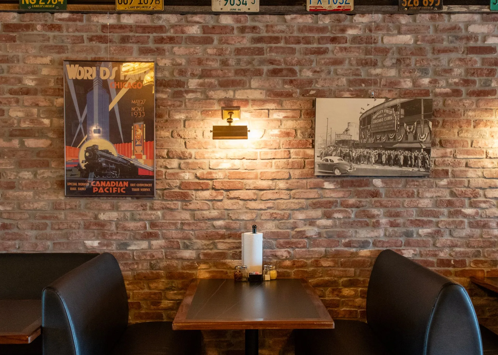 A corner table against exposed brick, with a Canadian Pacific travel poster and a framed train photograph above it