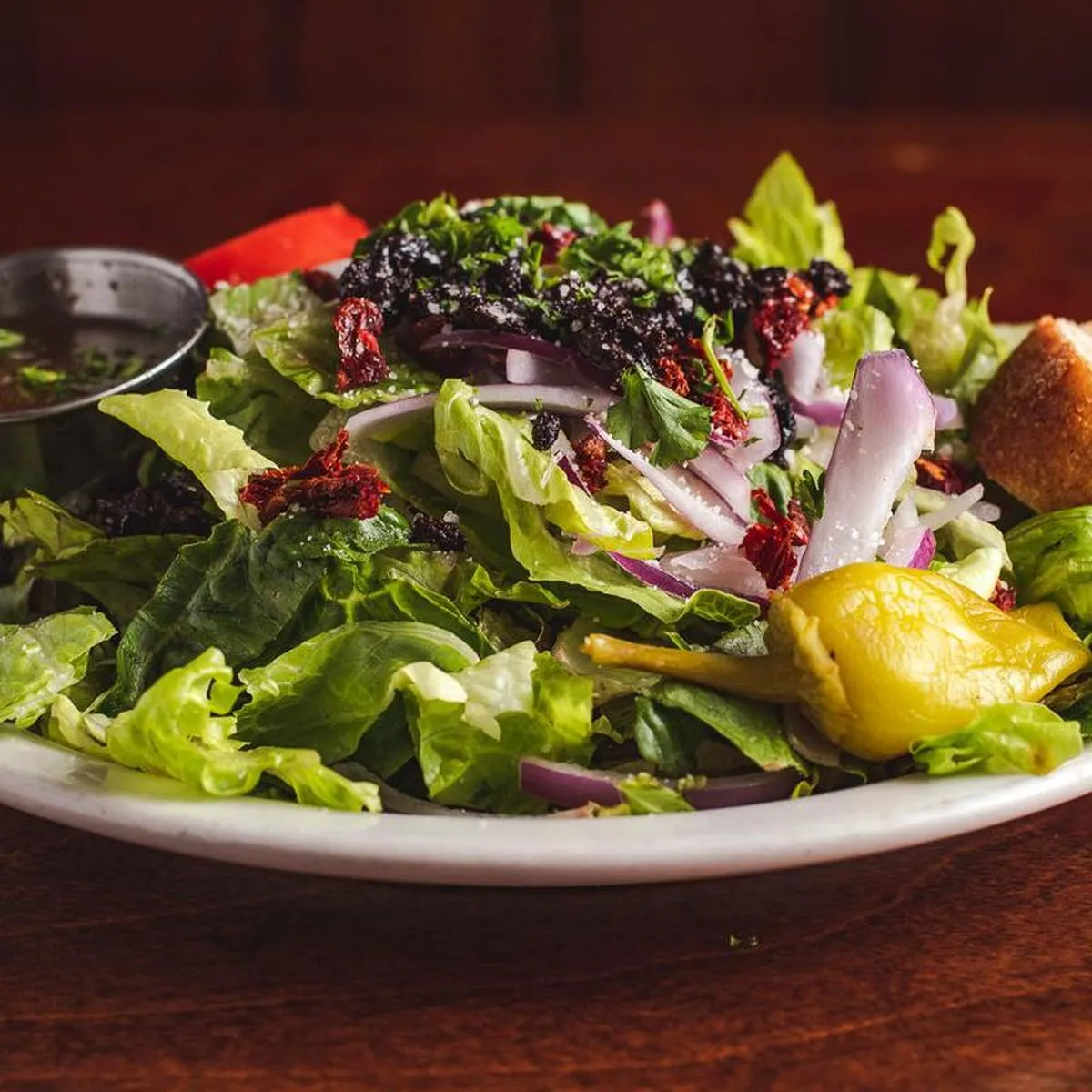 House salad with red onion, sun-dried tomato, olive tapenade and a pepperoncini