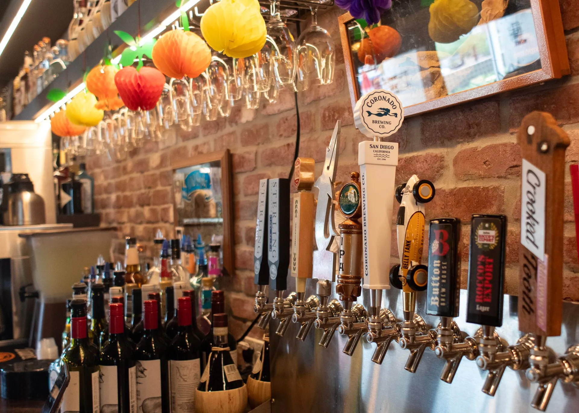 The bar, with a row of beer taps along the counter, wine bottles behind and glasses hanging above